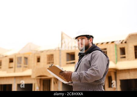Male architect drawing plan in notebook at construction site. Stock Photo