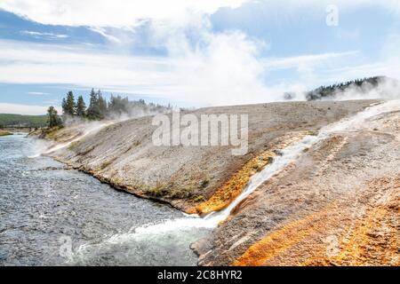 Hot water runoff from Excelsior Geyser flowing into the Firehole River at Yellowstone National Park's Midway Geyser Basin. Stock Photo