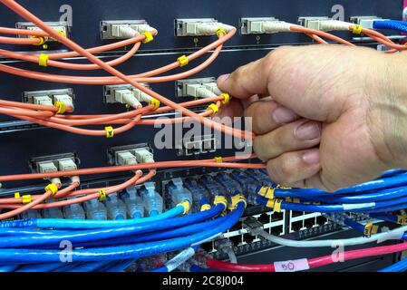 Technician connect fiber cable network to switch port in server room , Concept internet network management Stock Photo