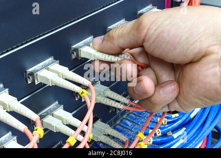 Technician connect fiber cable network to switch port in server room , Concept internet network management Stock Photo