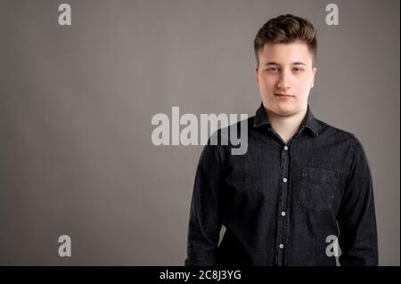 Portrait of serious stylish attractive man dressed with a casual black shirt isolated on grey background Stock Photo