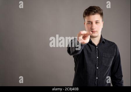Portrait of serious stylish attractive man dressed in casual black shirt doing I am watching you gesture posing on isolated black background with copy Stock Photo