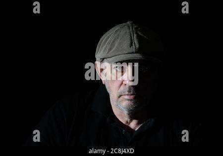 Portrait of elderly man in black clothes on a black background Stock Photo