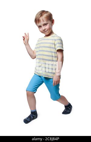 Boy in blue shorts and a yellow striped t-shirt posing in front of the camera Stock Photo