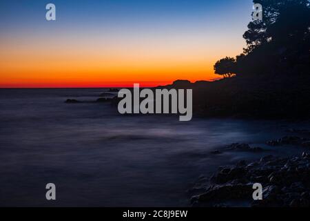 Beautiful evening on Adriatic Sea in Croatia, waves on rocks on shore of Dugi Otok island. Amazing sea sunset and red sky on horizon. Long exposure. Stock Photo