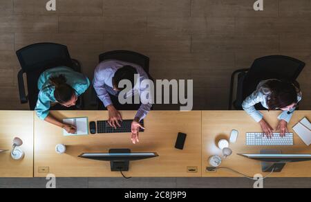 Top view of Asian Male customer care service working hard late in night shift at office,call center department,worker and overtime,team work with coll Stock Photo