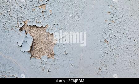 Uneven old wall surface closeup with flaking paint hole and rough cement layer underneath. Cracked painted texture of dilapidated building Stock Photo