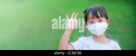 New normal :little girl wearing a cloth mask for protect from illness or Air pollution her raise hand ok posture Stock Photo