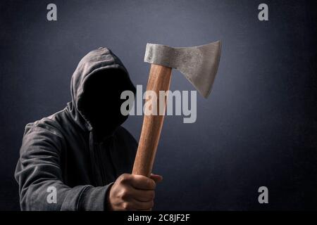 Hooded man with an axe in the dark Stock Photo