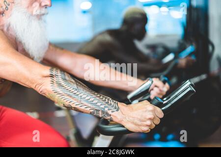 People from different generation and ethnicities doing workout session on cardio cyclette inside gym club - Fitness, spinning, healthy lifestyle and s Stock Photo