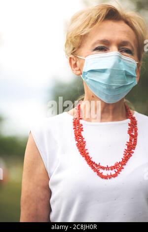 Portrait of a beautiful Blonde Woman Wearing a Mask. People walking dogs,  during Covid-19 pandemic, outdoor. Stock Photo
