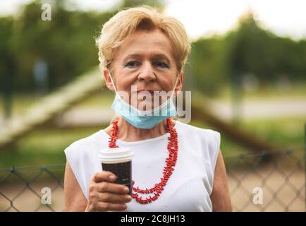 Portrait of a beautiful Blonde Woman Wearing a Mask. People walking dogs,  during Covid-19 pandemic, outdoor. Stock Photo