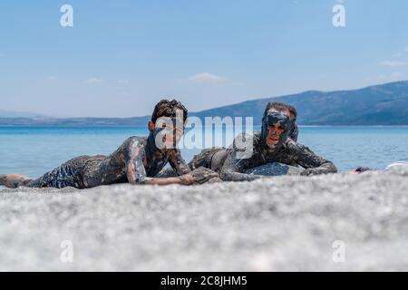 Burdur/Turkey - July 19 2020: Two boys lie by the lake Salda, covered in mud Stock Photo