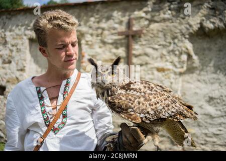 KEžMAROK, SLOVAKIA - Sep 17, 2019: Handsome young man is holding an owl on a glove at the Red Monastery in Slovakia Stock Photo