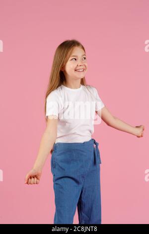 A little girl of 7 years in a white shirt on a pink background, emotions of joy and happiness. copy space. Stock Photo