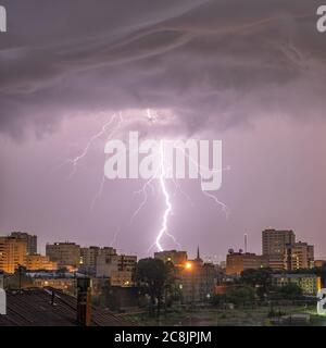 Photo of beautiful powerful lightning over big city, zipper and thunderstorm, abstract background, dark blue sky with bright electrical flash, thunder Stock Photo