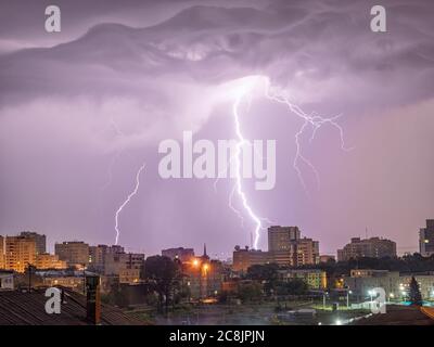 Photo of beautiful powerful lightning over big city, zipper and thunderstorm, abstract background, dark blue sky with bright electrical flash, thunder Stock Photo