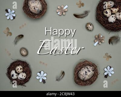 Natural quail eggs in the nests, feathers and easter decoration from natural materials. Overhead view with text: Happy Easter. Zero waste concept. Stock Photo