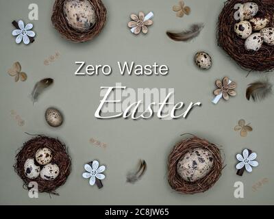 Natural quail eggs in the nests, feathers and easter decoration from natural materials. Overhead view with text: Zero Waste Easter. Stock Photo