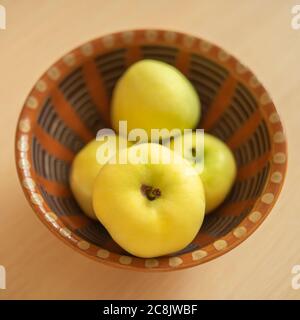 Ripe green apples in a brown clay bowl. Stock Photo