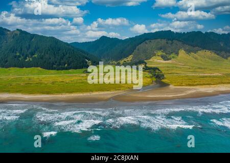 An aerial view of East Cape Campground next to the Pacific Ocean. Located on the eastern tip of the North Island of New Zealand. Mountains a forest le Stock Photo