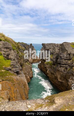 View out to sea over a blowhole at Pancake Rocks on Dolomite Point, South Island, New Zealand. Stock Photo