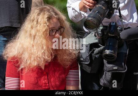 A young woman wearing spectacles stares at the cameras of a press photographer as fans and media await the arrival of Johnny Depp outside court. Stock Photo