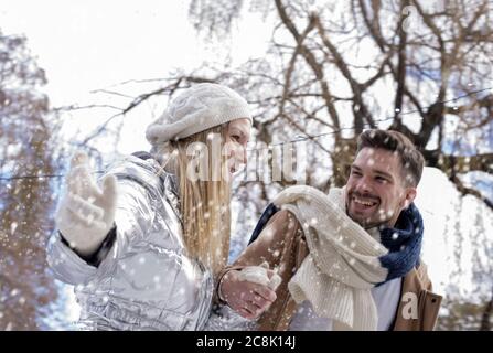 Young happy smiling couple enjoying the snowfall in the park Stock Photo