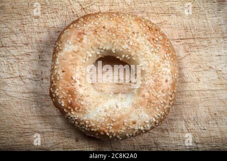 Sesame seeded bagel bread roll isolated on a wooden chopping board stock photo Stock Photo