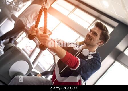 Young male doing hand stretching exercises with a rope at the gym Stock Photo