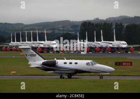 Glasgow, Scotland, UK. 23 July 2020. Pictured: A Cessna 510 Citation Mustang private biz jet (reg F-HIBF) seen against a backdrop of grounded British Airways (BA) Airbus A319/A320/A321 aircraft sit the second runway of Glasgow Airport awaiting their fate of being sold off or put in storage.  Since March these planes have been sitting idle on the the airports tarmac, doe to the global coronavirus (COVID19) crisis. Credit: Colin Fisher/Alamy Live News. Stock Photo