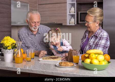 Little girl making pancakes with her grandparents Stock Photo