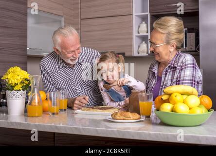 Little girl making pancakes with her grandparents Stock Photo