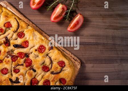 Traditional Italian Focaccia with cherry tomatoes, black olives and rosemary Stock Photo