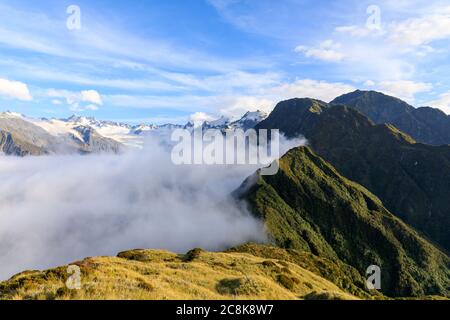 Mountain peaks in Franz Josef rising above a cloud inversion from the view of the summit of Alex Knob. Franz Josef Glacier, South Island, New Zealand. Stock Photo