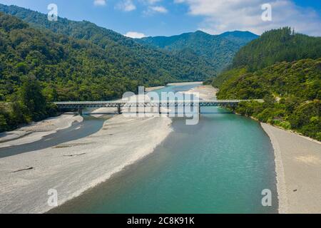 An aerial view of Pacific Coast Highway 35 bridge over the Motu River. Mountains a forest leading off into the background. Stock Photo