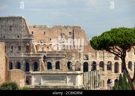 Rome, Italy. July, 2017.  Detail of the Colliseum  with visitors inside and the top of the Arch of Titus with latin inscriptions at the roman forum Stock Photo