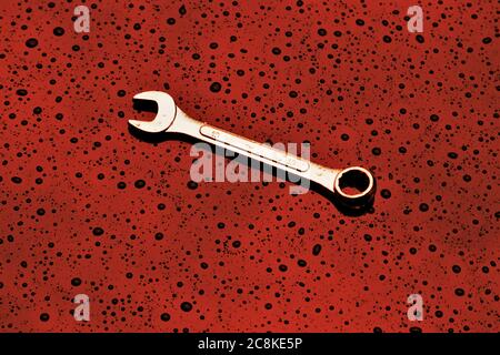 A single spanner on a textured red background Stock Photo