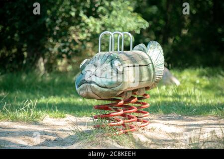 Wooden hand crafted fish spring rocker in a playground Stock Photo