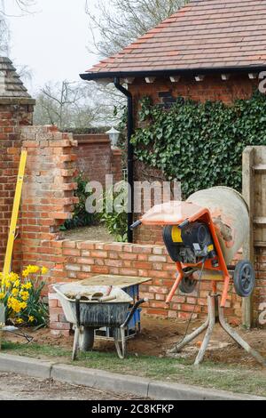 Building work at a house, a brick garden wall with cement mixer in UK Stock Photo