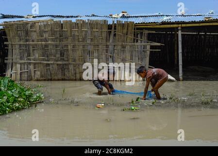 Dhaka, Bangladesh. 25th July, 2020. Children are catching fish in flooded area.The flood situation is worsening in Munshiganj. Due to the heavy rain, the water level of the Padma River has risen which resulted in a flood. At least 1.5 million people have been affected, with homes and roads in villages flooded. Flood Forecasting and Warning Centre (FFWC) officials have reported, the flood situation in 15 northern and central districts due to the rise in the water level of the main rivers. Credit: SOPA Images Limited/Alamy Live News Stock Photo