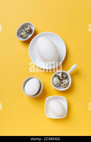 Easter eggs, natural chicken eggs, quail eggs and chocolate eggs on white plates. Festive time Stock Photo