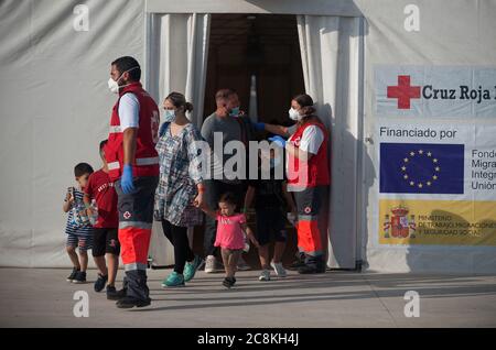 Algerian migrants leave a tent of the Spanish Red Cross while wearing face masks after being intercepted by Spanish Civil Guards authorities on the Mediterranean Sea.A Spanish Civil Guard vessel intercepted around 82 Algerian migrants near Almeria's coast while trying to reach Europe by small boats. During the coronavirus pandemic, the closure of Morocco's border with Spain as a measure to prevent the spread of coronavirus disease has caused a drastic drop in the number of migrants that try to reach the Spanish coasts across Alboran Sea route, while the arrival of migrants to Canary Islands co Stock Photo