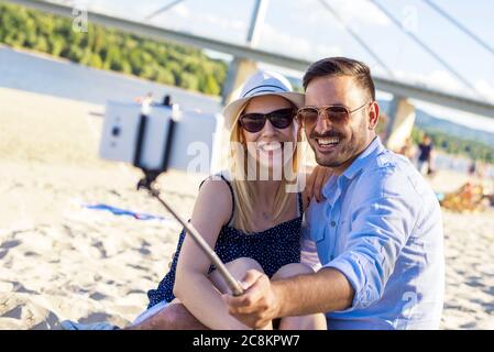 Shallow focus shot of a happy couple taking a selfie on a sandy beach Stock Photo