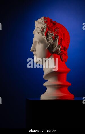 Plaster statue bust of Apollo Belvedere in red and blue light on a blue background Stock Photo