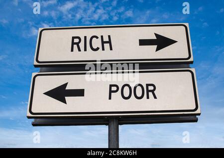 Rich and poor road sign. White two street signs with arrow on metal pole with word. Directional road. Crossroads Road Sign, Two Arrow. Blue sky