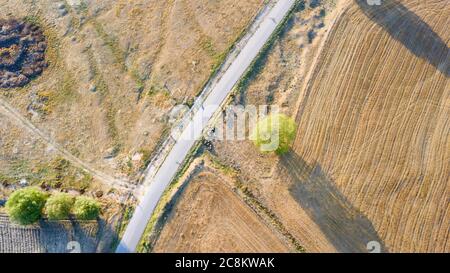 Aerial view of flock of sheep, goat and lamb. Sheeps are eating in the fields. There is also black color sheeps too. They are near the empty road. Stock Photo