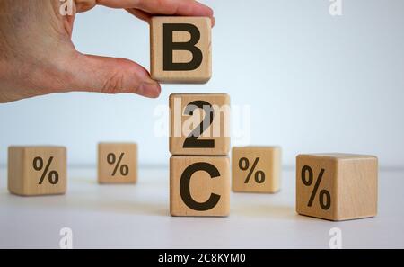 Male hand placing a cube with letter B on top of a other cubes. B2C text. Beautiful white background. Stock Photo