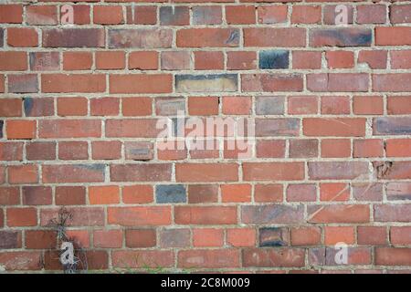 Old vintage wall with many red bricks, and some black bricks Stock Photo