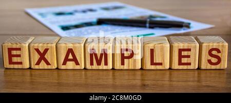 Concept word 'examples' on cubes on a beautiful wooden table, pen and documents. Stock Photo